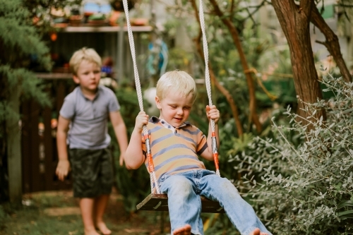 Kids playing on backyard swing - Australian Stock Image