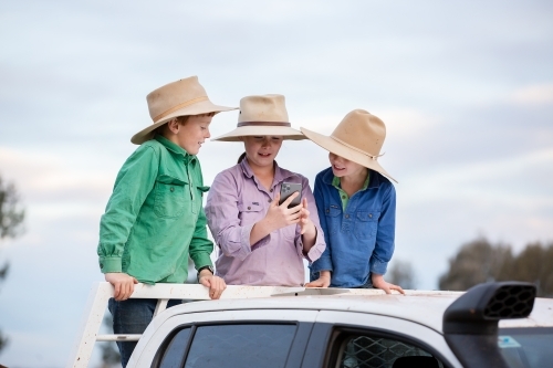 Kids use a phone to take photos on the back of a ute - Australian Stock Image