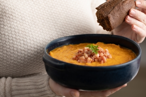 Lady holding bowl of soup with rye bread - Australian Stock Image