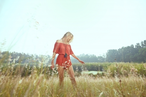 Lady in red walking in a field of grass