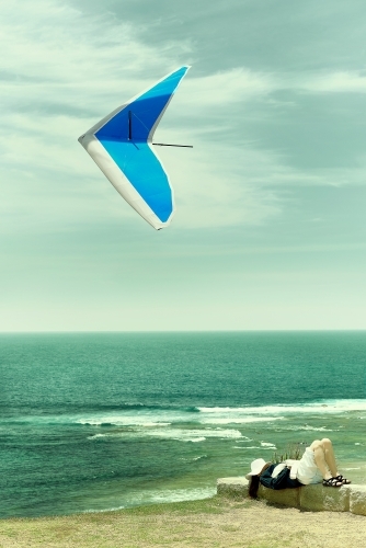 Lady resting with hang glider above on a beautiful day - Australian Stock Image