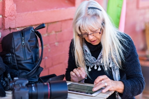 lady tourist with long blonde hair typing on tablet - Australian Stock Image