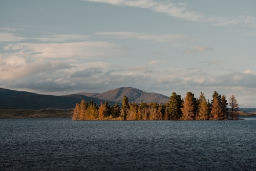 Lake Jindabyne at sunset with autumn coloured trees and mountains - Australian Stock Image