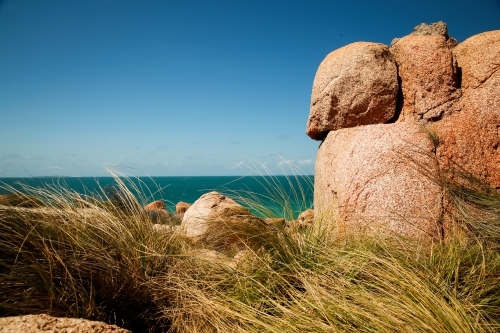 Large, rounded boulders behind the tall grasses - Australian Stock Image