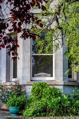 Large window of sandstone building with gardens around - Australian Stock Image