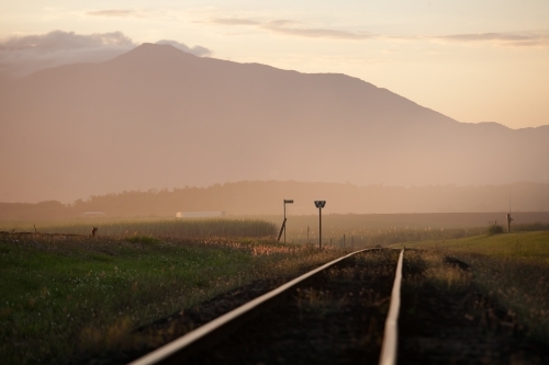 Late afternoon light on cane train tracks with mountains in background - Australian Stock Image