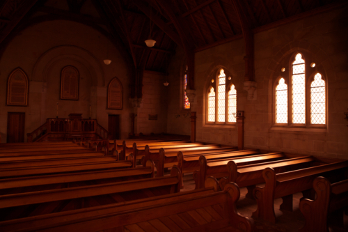 Light streams through a stained glass window onto pews in an old church in Ross, Tasmania - Australian Stock Image