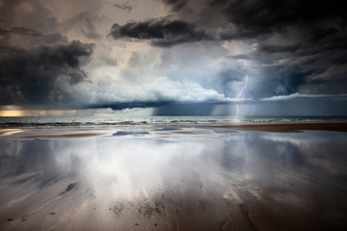 Lightning and storm clouds over the beach in Darwin with reflection - Australian Stock Image