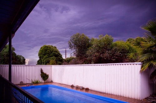 Lightning striking behind suburban pool and backyard