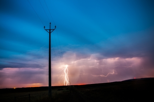 Lightning striking in ominous sky behind power pole