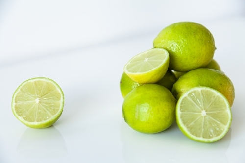Lime fruit on white, ready to juice for cool summer drink - Australian Stock Image