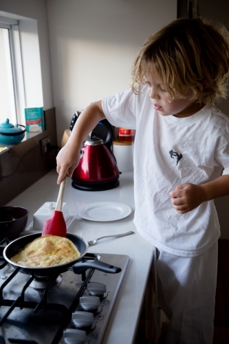 Little boy cooking omelette - Australian Stock Image