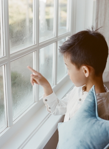 Little boy holding a star looking out of the window - Australian Stock Image