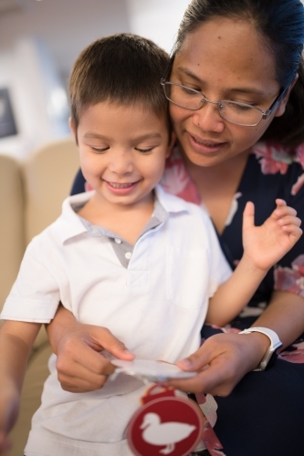 Little boy opening Christmas presents at home - Australian Stock Image