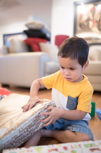 Little boy opening Christmas presents at home