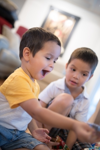 Little boy opening Christmas presents at home - Australian Stock Image