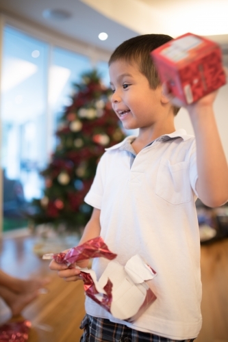 Little boy opening Christmas presents at home - Australian Stock Image