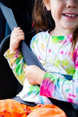 Little girl happily wearing seat belt in booster seat in car - Australian Stock Image