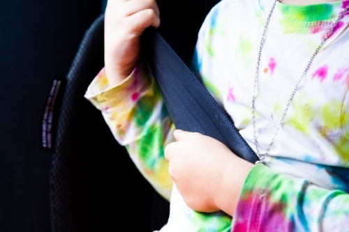 Little girl happily wearing seat belt in booster seat in car - Australian Stock Image