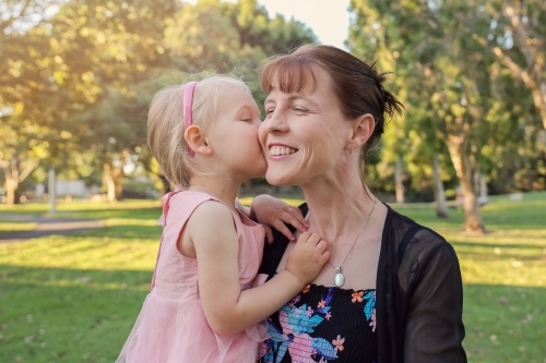 Little girl kissing her mother in the park