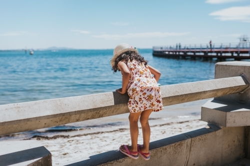 Little girl looking at the sea over railing - Australian Stock Image