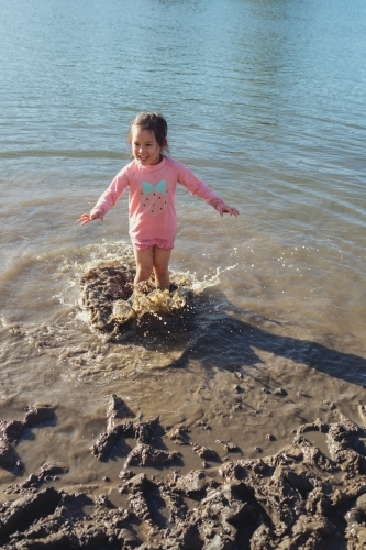 Little girl playing in the muddy beach - Australian Stock Image