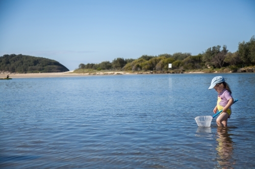 Little girl playing in the water where the river meets the sea - Australian Stock Image