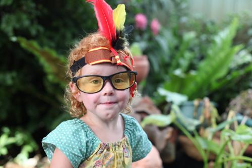 Little girl wearing dress up Indian headband and glasses - Australian Stock Image