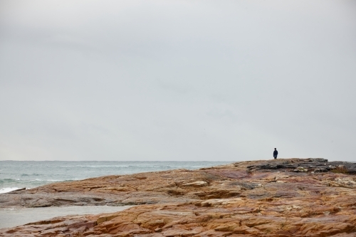 Lone person at coastal landscape on overcast day - Australian Stock Image