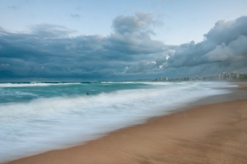 Lone surfer in waves with Cronulla in the background - Australian Stock Image