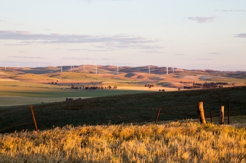 looking across green valley to wind turbines - Australian Stock Image