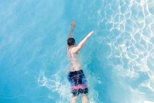 Looking down at man swimming freestyle in pool - Australian Stock Image