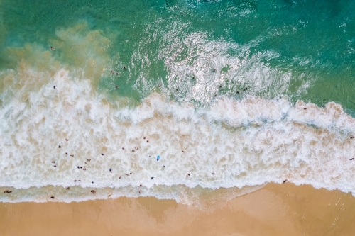 Looking down at multiple swimmers on a busy beach day - Australian Stock Image