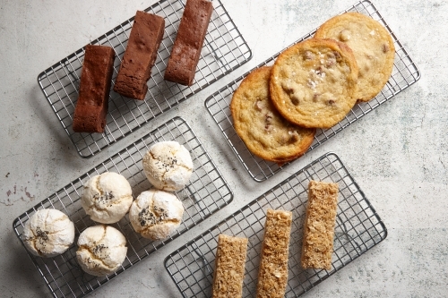 Looking down on four baking racks of baked treats at cafe - Australian Stock Image