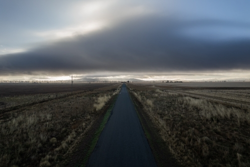 Looking down on the empty countryside road as the storm approaches - Australian Stock Image