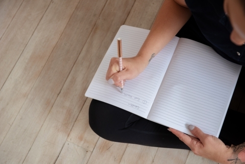 looking down woman journalling goal setting in yoga clothes - Australian Stock Image