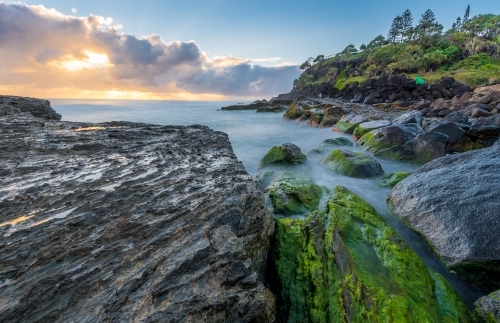 Looking out at choppy ocean from textured mossy rocks - Australian Stock Image