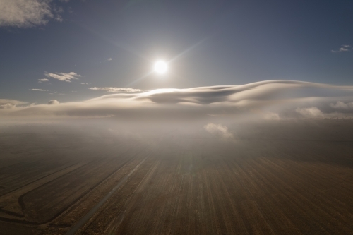 Looking over the fog clouds with the sun above at the fields ready for cropping - Australian Stock Image