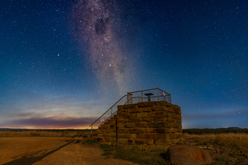 Looking up at the milky way galaxy above a stone lookout platform against the night sky - Australian Stock Image