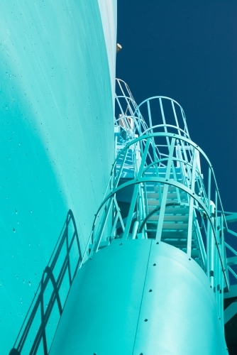 Looking up at view of blue stairs climbing up the side of a structure - Australian Stock Image