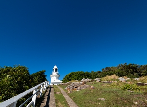 Looking up path to white lighthouse with deep blue sky - Australian Stock Image