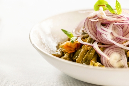 Loubieh Bzeit served in a ceramic dish topped with sliced red onions. - Australian Stock Image