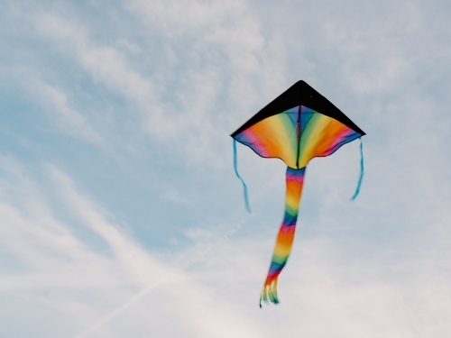 Low-angle shot of flying rainbow kite - Australian Stock Image