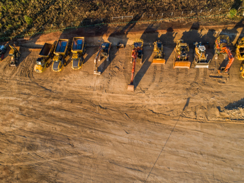 Machinery on worksite lined up in morning light ready to continue construction on bypass road - Australian Stock Image