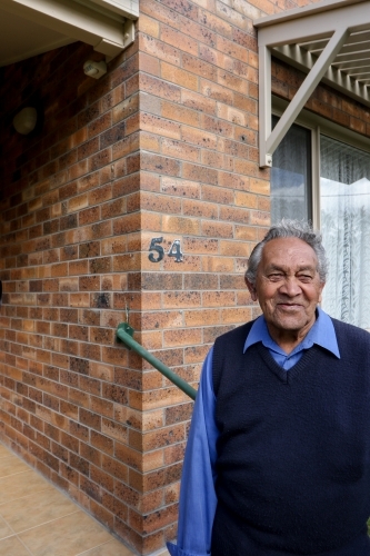 Male Aboriginal elder standing in front of his home - Australian Stock Image