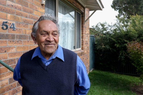 Male Aboriginal elder standing in front of his home - Australian Stock Image