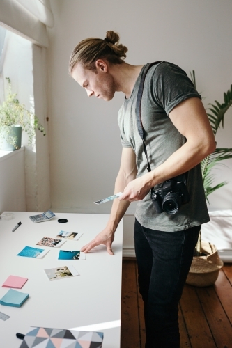 Male photographer reviewing prints in his studio - Australian Stock Image