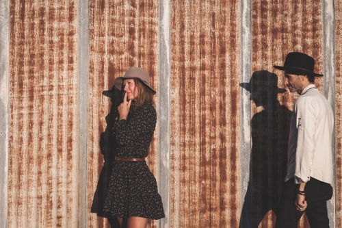 Man and woman standing against rusted iron wall - Australian Stock Image