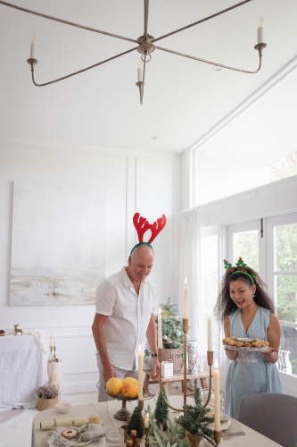 Man and woman standing beside Christmas-decorated table - Australian Stock Image