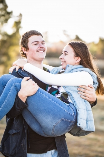 Man carrying girlfriend in his arms laughing - Australian Stock Image